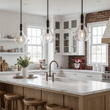 Three black mini pendant lights with bubble glass shades hang over a kitchen island