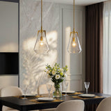 Two gold pendant lights with clear glass shades hang over a dining table