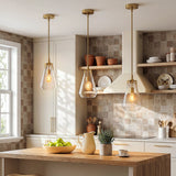 Three gold pendant lights with clear glass shades hang over a wooden kitchen island
