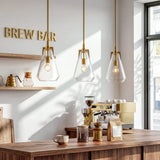 Three gold pendant lights with clear glass shades hang over a wooden coffee bar