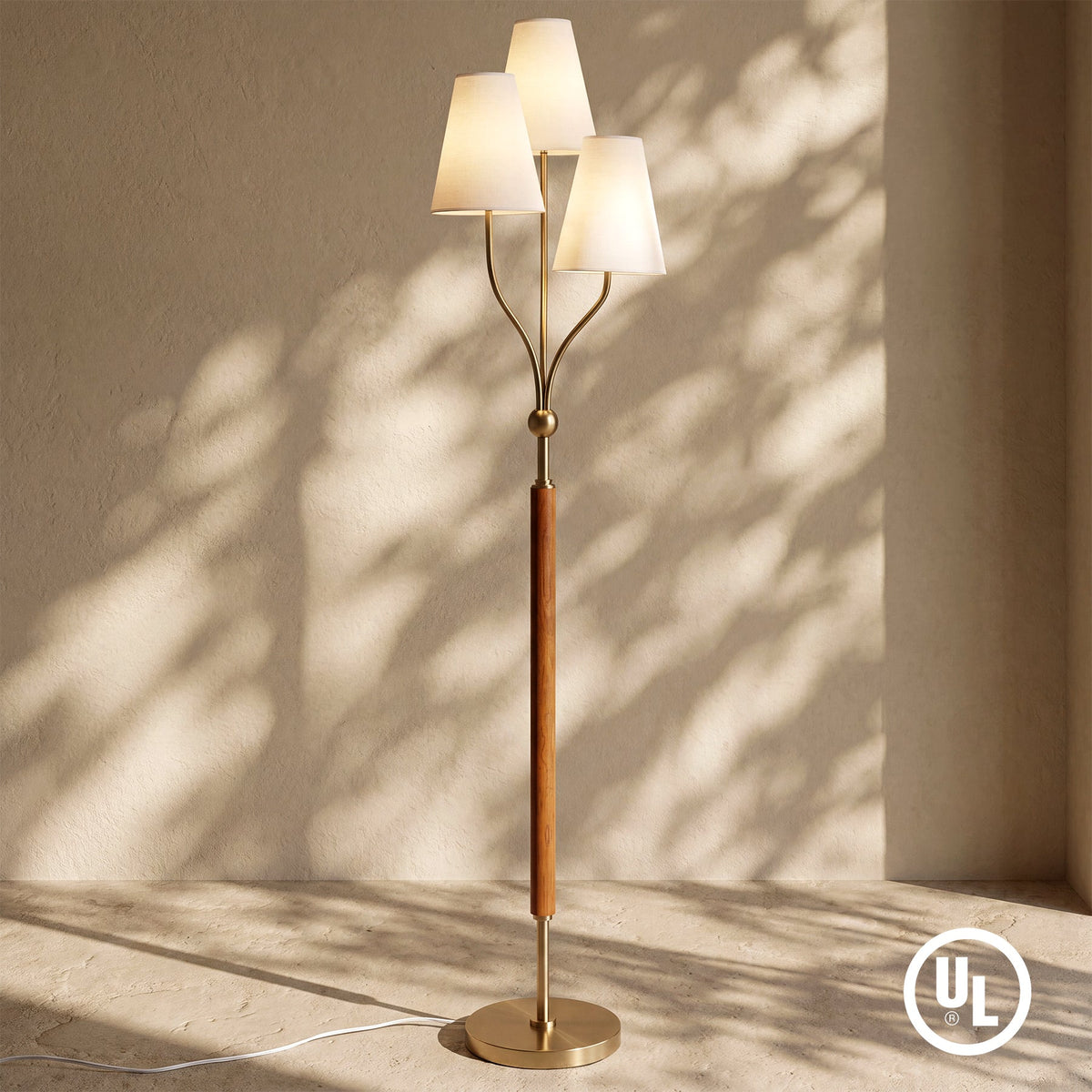 Gold floor lamp with three linen shades and rubberwood handle, angled view in natural light