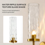 Gold wall sconce with water ripple glass shade, lit, shown at angle