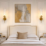 Two gold wall sconces with water ripple glass, mounted on bedroom wall flanking a bed