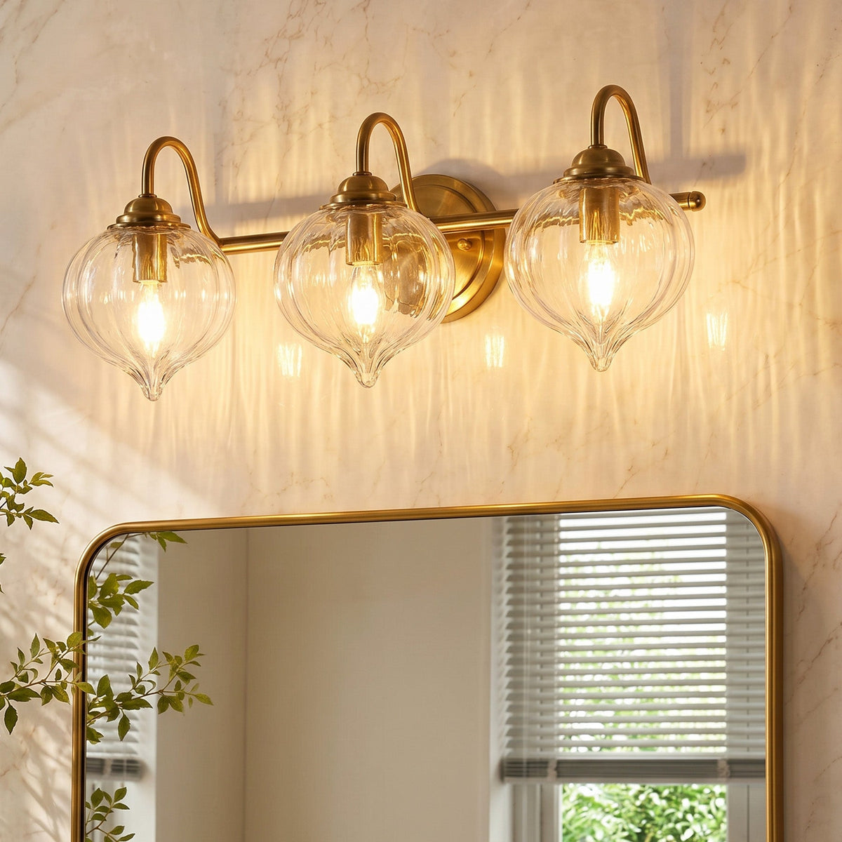 Gold bathroom vanity light with three pumpkin-shaped glass shades mounted above a mirror