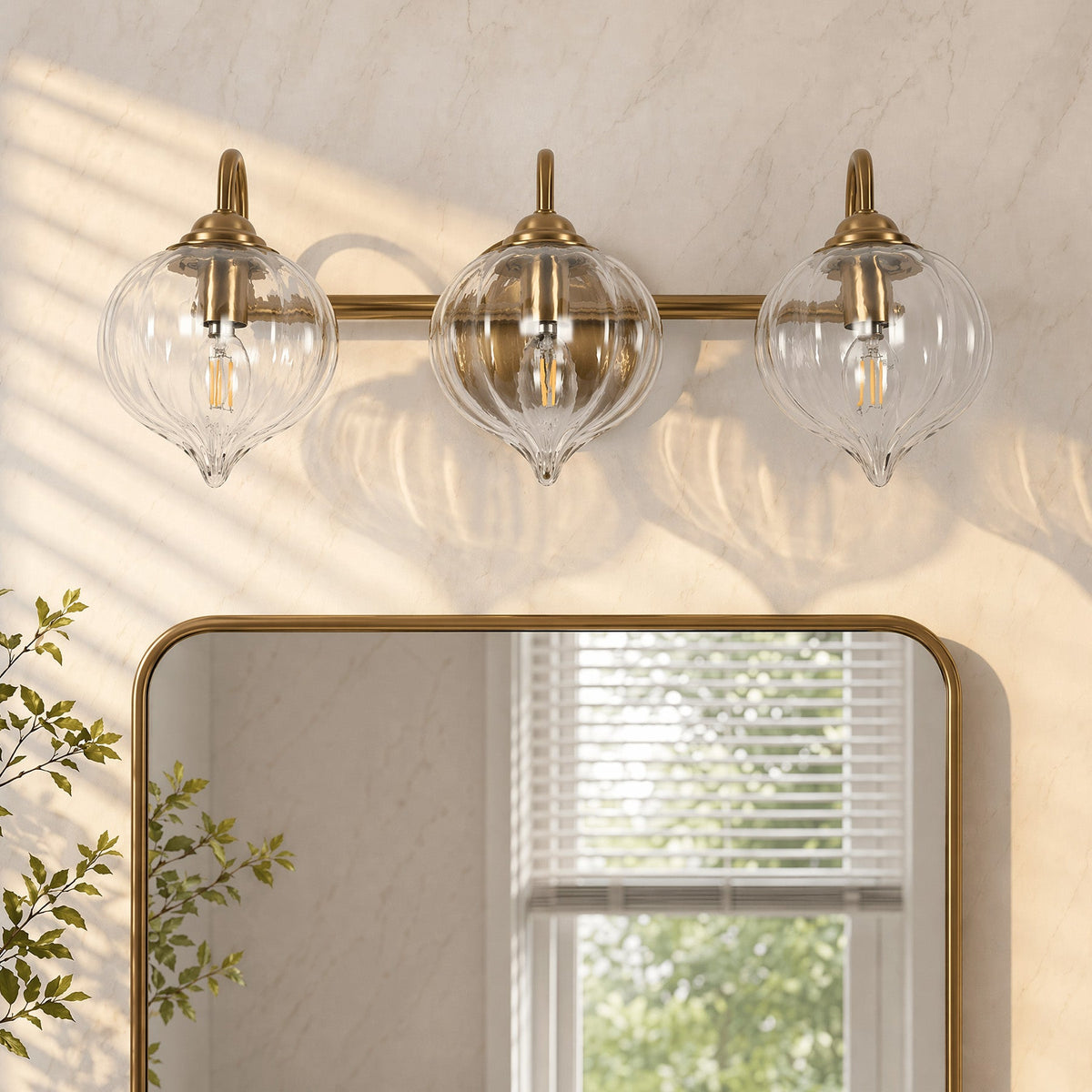 Gold bathroom vanity light with three pumpkin-shaped glass shades above a mirror