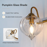 Gold bathroom vanity light with three pumpkin glass shades, shown at an angle