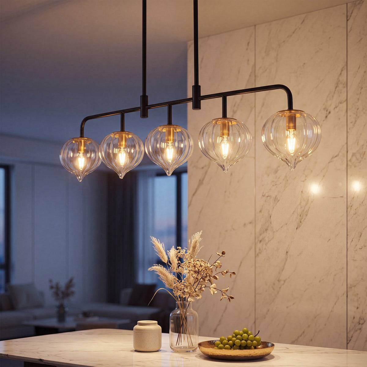 Five-light linear kitchen island light with clear ribbed glass shades and black metal frame, hanging over marble countertop