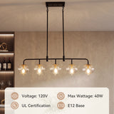 Five-light linear pendant with black metal frame and clear ribbed glass shades, hanging in a kitchen setting