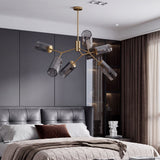 Gold branch chandelier with six smoky gray glass shades hanging over a bed in a modern bedroom