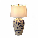 Blue and white porcelain table lamp with beige burlap shade, shown from front angle