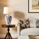 Blue and white porcelain table lamp with cream shade on wooden side table beside sofa