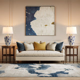 Blue and white porcelain table lamp with burlap shade on wooden side table beside sofa