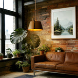 Gold drum pendant light with industrial metal shade hanging in a brick-walled room